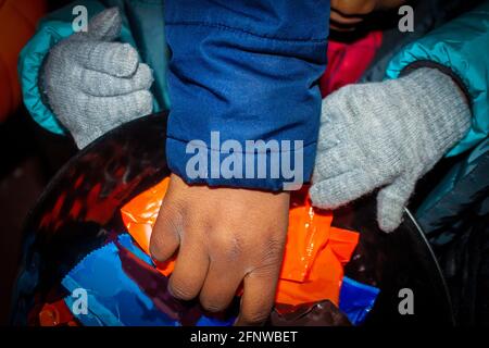 Afroamerikanische Kinder, die in eine Schüssel greifen, um Süßigkeiten zu bekommen Halloween - Nahaufnahme Stockfoto