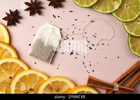 Zitronenscheiben, Limetten-, Zimt- und Anissterne auf rotem Hintergrund. Hintergrund-Strukturmuster. Draufsicht. Teebeutel in der Mitte. Stockfoto