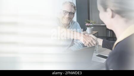 Zusammensetzung aus lächelndem Geschäftsmann und Geschäftsfrau, die im Büro die Hände schüttelt Mit Bewegungsunschärfen Stockfoto