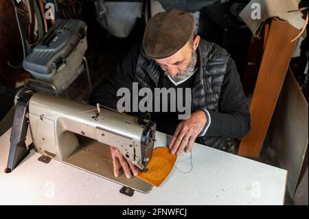 Draufsicht alter Mann in der Werkstatt, der Lederwaren beim Arbeiten herstellt Mit Nähmaschine Stockfoto