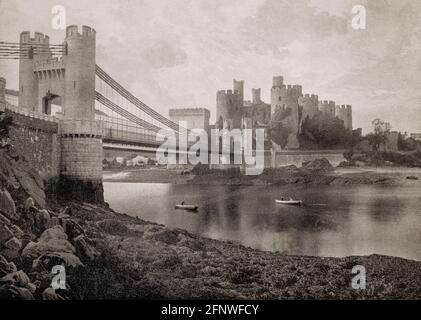 Blick auf die Conwy Suspension Bridge aus dem späten 19. Jahrhundert, die den Fluss Conwy überspannt, entworfen von Thomas Telford und 1826 fertiggestellt. Telford entwarf die Stütztürme der Brücke, die den Türmen von Conwy Castle auf dem gegenüberliegenden Ufer entsprechen. Die Burg wurde auf Anweisung von Edward I. von England zwischen 1283 und 1289 als Teil seiner Eroberung des Fürstentums Wales erbaut. Stockfoto