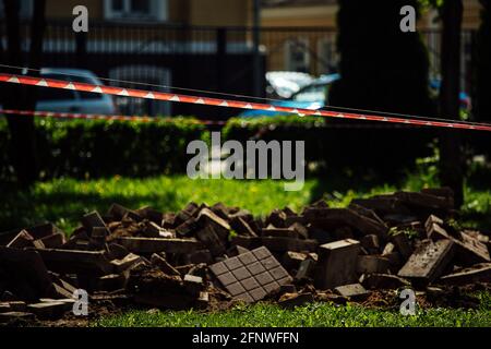 Ein Warnband verbietet den Durchgang. Absperrband um den gefährlichen Ort. Reparaturarbeiten an der Stelle des Asphaltausfalls nach der Katastrophe. Absperrband Stockfoto