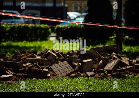 Ein Warnband verbietet den Durchgang. Absperrband um den gefährlichen Ort. Reparaturarbeiten an der Stelle des Asphaltausfalls nach der Katastrophe. Absperrband Stockfoto