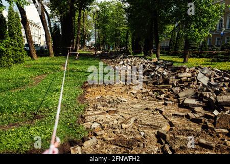 Ein Warnband verbietet den Durchgang. Absperrband um den gefährlichen Ort. Reparaturarbeiten an der Stelle des Asphaltausfalls nach der Katastrophe. Absperrband Stockfoto