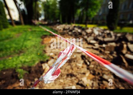 Ein Warnband verbietet den Durchgang. Absperrband um den gefährlichen Ort. Reparaturarbeiten an der Stelle des Asphaltausfalls nach der Katastrophe. Absperrband Stockfoto