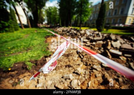 Ein Warnband verbietet den Durchgang. Absperrband um den gefährlichen Ort. Reparaturarbeiten an der Stelle des Asphaltausfalls nach der Katastrophe. Absperrband Stockfoto