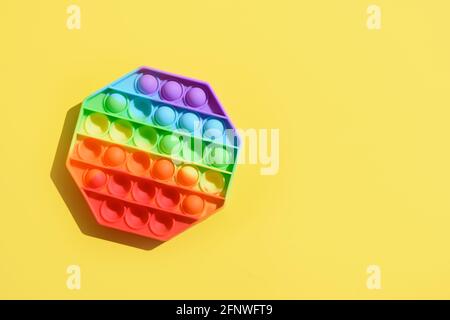Neue beliebte Silikon bunte Antistress Pop es Spielzeug für Kind auf gelbem Hintergrund. Stockfoto
