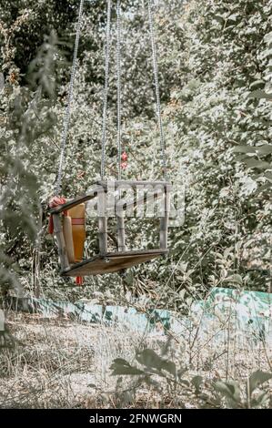 Eine überwuchert und verlassene Schaukel mitten im Wald. Viel Gras. Die Natur übernimmt. Seltsame Gefühle. Stockfoto