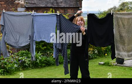 Frau hängend Waschen an Wäscheleine mit Haken im Garten Großbritannien, Großbritannien. Trocknen außerhalb des Außenhaushalts Hausarbeiten Arbeitsplätze Frauen Frauen Mutter Frau Stockfoto