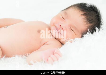 Porträt eines einmonatigen schlafenden, neugeborenen Mädchens auf einer weißen Decke. Konzept Porträt Studio Mode Neugeborenen. Stockfoto