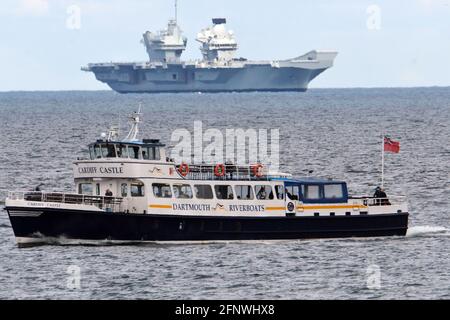 Brixham, Großbritannien. Mai 2021. An einem warmen Nachmittag in Brixham South Devon steht die HMS Prince of Wales auf der Horizion und stellt die Dartmouth-Fähre von Cardiff Castle in den Schatten. Die HMS Ptince of Wales ist ein Flugzeugträger der Queen Elizabeth-Klasse, eines der mächtigsten Surface-Kriegsschiffe, die jemals im Vereinigten Königreich gebaut wurden. Flugdeck 70 Meter breit 280 Meter lang, Platz für drei Fußballplätze, Lebensmittelaufbewahrung 45 Tage, Besatzung von ca. 1,600 Personen inklusive Flugzeugpersonal, kann vier Merlin Helicopters tragen. Bildquelle: Robert Timoney/Alamy Live News Stockfoto