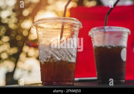 Eisamericano-Kaffee aus Plastikglas aus asiatischem Straßencafé mit Außenbeleuchtung. Stockfoto