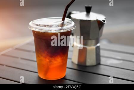 Eisamericano-Kaffee aus Plastikglas aus asiatischem Straßencafé mit Außenbeleuchtung. Stockfoto
