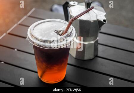 Eisamericano-Kaffee aus Plastikglas aus asiatischem Straßencafé mit Außenbeleuchtung. Stockfoto