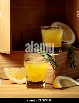 Traditioneller hausgemachter Zitronenlikör Limoncello und frische Zitrusfrüchte und Rosmarin. Stockfoto