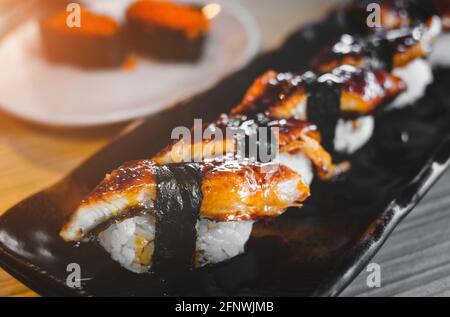 Japanisches Aal-Sushi vom Grill oder Unagi, serviert mit dezenter Beleuchtung im Innenbereich. Stockfoto