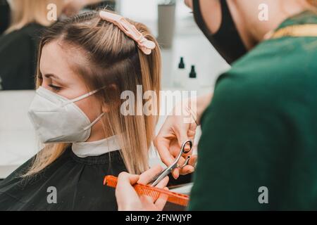 Haarpflege, Frisör schneidet die geschnittenen Enden der Haare und richtet die Länge, die Arbeit der Friseure während der globalen Coronavirus-Pandemie.neu Stockfoto