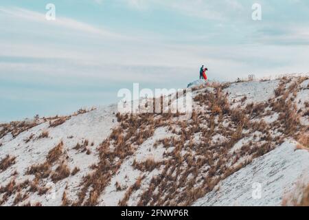 Schönes Paar geht in den phosphatweißen Bergen der Ukraine, das Mädchen in einem roten Kleid. Stockfoto