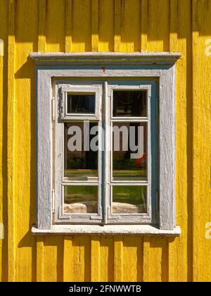 Altes, abgenutztes, weißes Fenster in der Nähe der Außenansicht, Blick aus Holz, gelb Haus auf dem Lande Stockfoto