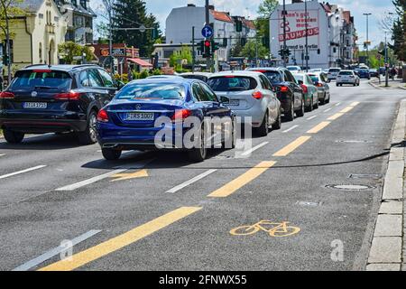 Berlin, Deutschland - 8. Mai 2021: Straßenszene mit temporär bemaltem Radweg in Berlin. Der Fokus liegt auf dem gelben Fahrradsymbol auf dem Asphalt. Stockfoto