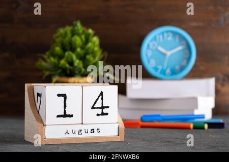 August. August 14 Holzwürfelkalender mit unscharfen Objekten auf dem Hintergrund. Stockfoto