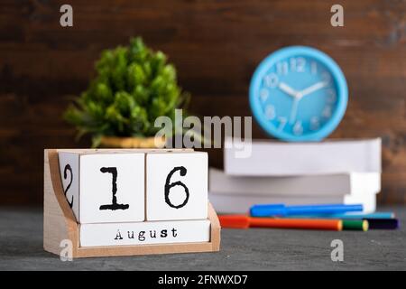 August. August 16 Holzwürfelkalender mit unscharfen Objekten auf dem Hintergrund. Stockfoto