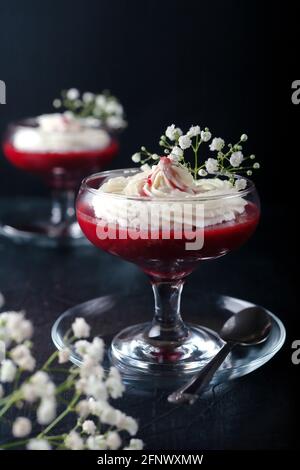 Himbeer-Erdbeer-Dessert mit Käsecreme in verrin auf einem schwarzen Hintergrund Stockfoto