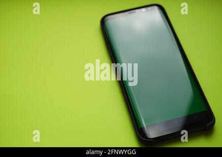 Schwarzes Smartphone in einem alcantara-Gehäuse auf einem grünen Tisch. Stockfoto