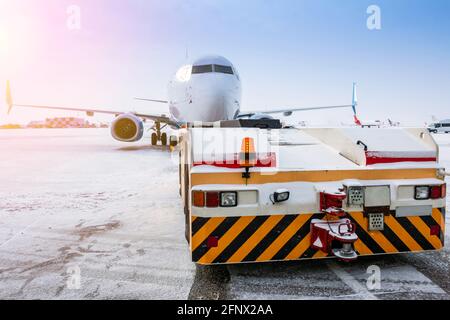 Der Schlepper schiebt das Passagierflugzeug im kalten Winter flughafenvorfeld Stockfoto