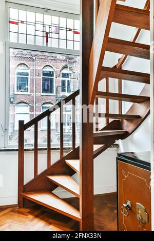 Elegante Wendeltreppe aus Holz, die Ebenen der Wohnwohnung miteinander verbindet Gebäude im Vintage-Stil Stockfoto