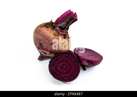 Ganze blattlose rohe rote Rübenwurzel und die Rübe schneiden in die Hälfte auf die weiße Oberfläche. Konzept für frisches Gemüse. Stockfoto