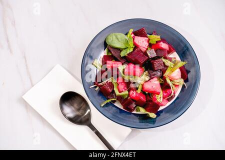 Salat aus Rüben, Ananas und Zichorien mit Olivenöl und Basilikum auf einem Teller auf weißem Marmorboden. Frisches und gesundes Gemüse Konzept. Stockfoto