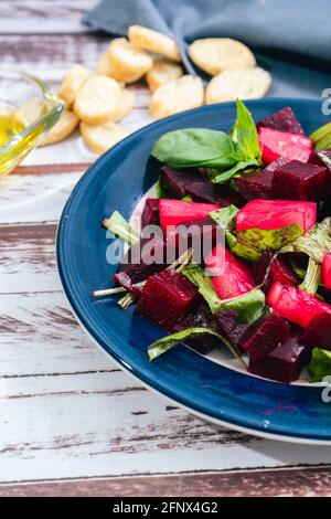 Salat aus Rüben, Ananas und Zichorien mit Olivenöl und Basilikum auf einem Teller auf einem rustikalen Tisch im Still-Life-Stil. Konzept für frisches Gemüse. Stockfoto