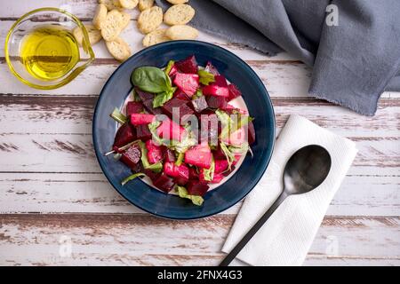 Salat aus Rüben, Ananas und Zichorien mit Olivenöl und Basilikum auf einem Teller auf einem rustikalen Tisch im Still-Life-Stil. Konzept für frisches Gemüse. Stockfoto