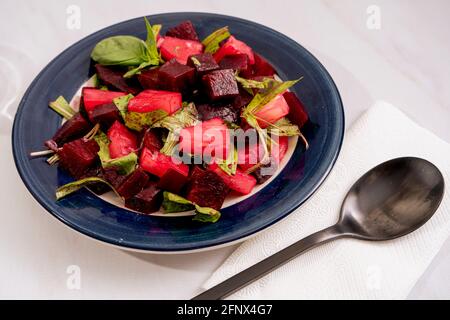 Salat aus Rüben, Ananas und Zichorien mit Olivenöl und Basilikum auf einem Teller auf weißem Marmorboden. Frisches und gesundes Gemüse Konzept. Stockfoto
