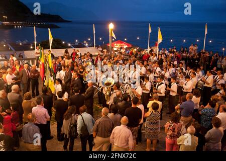 Menschen, die während nächtlicher Feierlichkeiten in Ribeira Quente der portugiesischen Marschkapelle lauschen. Sao Miguel, Azoren, Portugal. Stockfoto