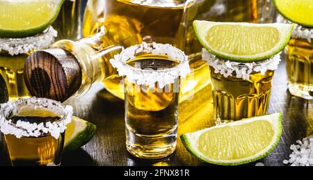 Mehrere Gläser mexikanischen Gold Tequila mit Zitrone und Salz Auf Holztisch Stockfoto