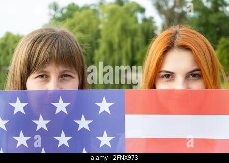 Porträt zweier junger Frauen, die ihre Gesichter hinter der US-Nationalflagge verbergen. Stockfoto