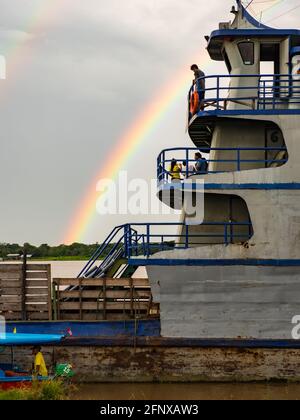 Amazonas, Peru - 07. Dezember 2019: Blick auf das langsame Boot 'Maria Fernanda' und Regenbogen im kleinen Hafen am Amazonas. Amazonien. Südamerika Stockfoto