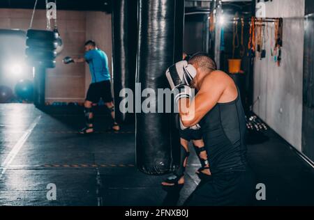 Junge Muskel Boxer mit einem Boxsack in der Turnhalle. Boxer schlagen Stanzgeschwindigkeit Tasche Stockfoto