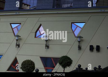 Ungewöhnliche unregelmäßige geometrische Formen der Fenster spiegeln den Abendhimmel wider. Stockfoto