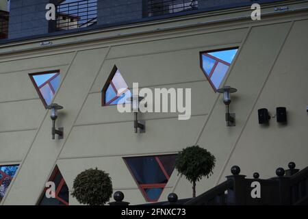 Ungewöhnliche unregelmäßige geometrische Formen der Fenster spiegeln den Abendhimmel wider. Stockfoto