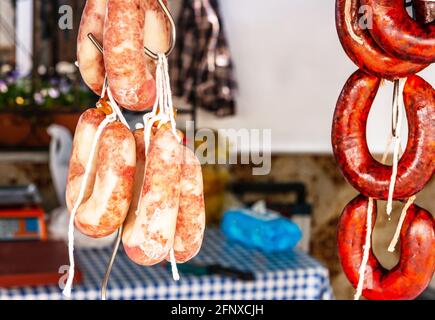 Typische spanische Würste hängen an einem Dorfstand am Lebensmittelmarkt, traditionelle Fleischprodukte Stockfoto