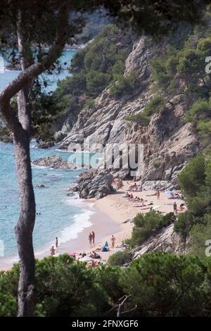 Touristen ruhen sich aus und schwimmen in einer abgeschiedenen Bucht an der Costa Brava An geheimen europäischen Stränden Stockfoto