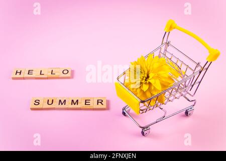 Hallo Sommer. Warenkorb mit Blumen. Gelbe Blume auf einem rosa Hintergrund. Stockfoto