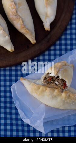 Traditionelle argentinische Empanadas, gefüllt mit salzigem Fleisch, Oliven, Zwiebeln, rotem Pfeffer, Ei, Gewürze, die alle in einer knusprig gebackenen Schicht verpackt sind, sind bereit zum Genießen! Stockfoto