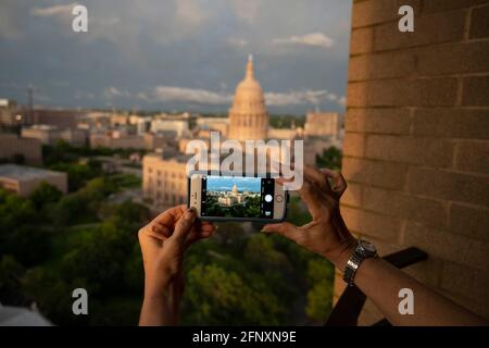 Eine Frau nimmt ein Handy-Bild auf, während eine Bank von Mammatuswolken einem Regensturm über der Kuppel des Texas Capitol in Austin folgt, während ein Frühlingssystemdurchweht, das durch Zentral-Texas weht. Die Mammatokumulus zeichnen sich durch baumwollartige Schwellungen und dramatische Formationen aus. ©Bob Daemmrich Stockfoto