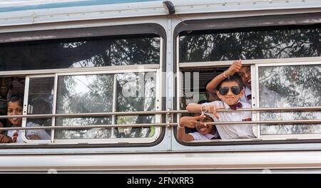 Srilankische Schüler gestikulieren, geben Friedensschilder aus dem Busfenster, Anuradhapura, Sri Lanka Stockfoto