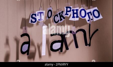 An Fäden hängende Buchstaben bilden in einer gewissen Unordnung das Alamy-Logo. Stockfoto