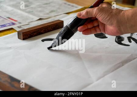 Ein Kalligraph schreibt Kalligrafie-Zeichen mit einem großen Pinsel, einer Nahaufnahme des Pinsels. Übersetzung: Die Höhen sind zu kalt Stockfoto